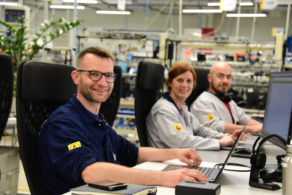 One woman and two men working at Scanfil factory